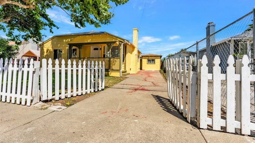 View of front of property featuring a fenced front yard, a gate, and covered porch