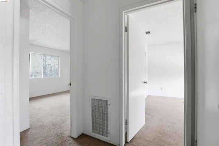 Hall featuring light colored carpet and a textured ceiling