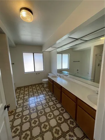 Dual sink full bathroom equipped with pull out hamper for towels