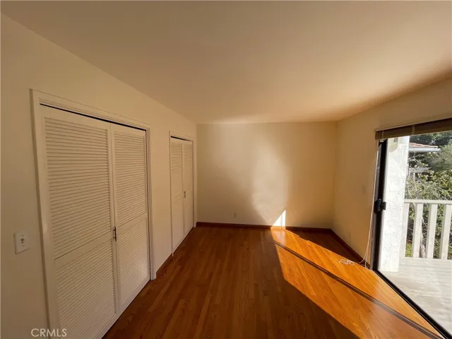 Bedroom equipped with wood floors, two closets, and a balcony accessed through sliding glass doors