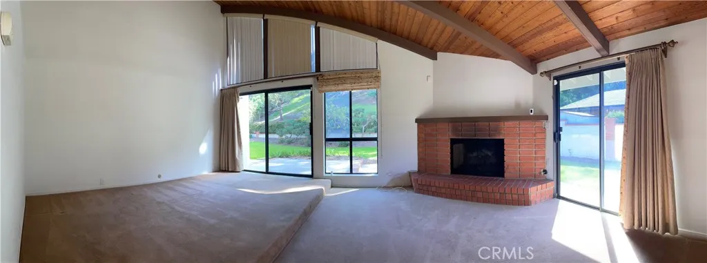 Panoramic view of the master bedroom equipped with fireplace, 2 large glass sliding doors, and slanted wood ceiling