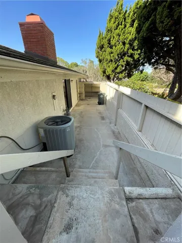 Lower area behind a small gate that houses the HVAC unit and landscaping area