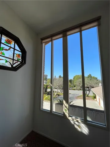 Stained glass window flanked by one of two large windows halfway up the staircase