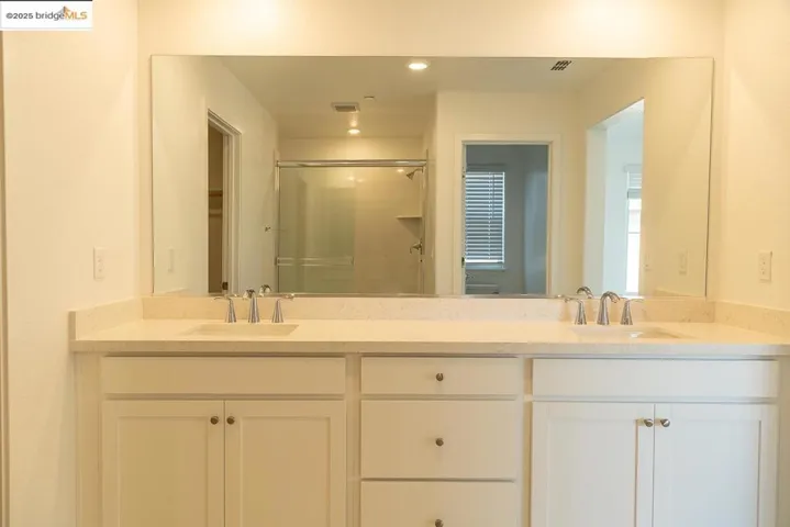 Full bathroom with double vanity, a stall shower, and recessed lighting