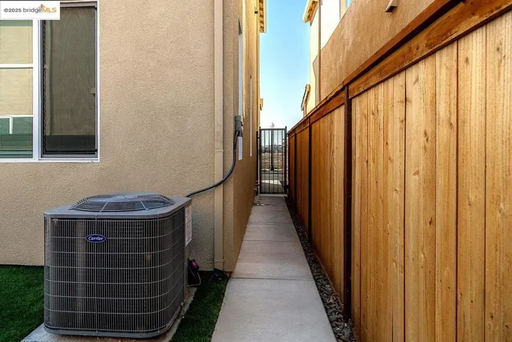 View of side of home with a gate and stucco siding