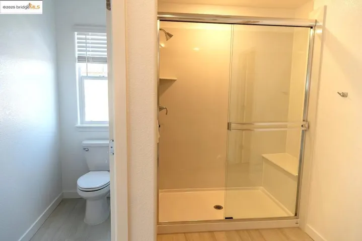 Full bath with a stall shower and a textured wall