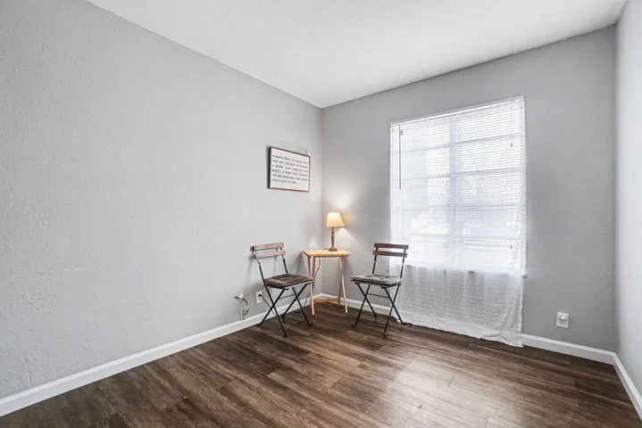 Sitting room with dark wood finished floors and a textured wall