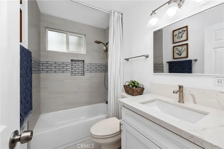 Hallway bathroom with tub/shower combo, upgraded with modern tile finishes and sleek glass inlays.