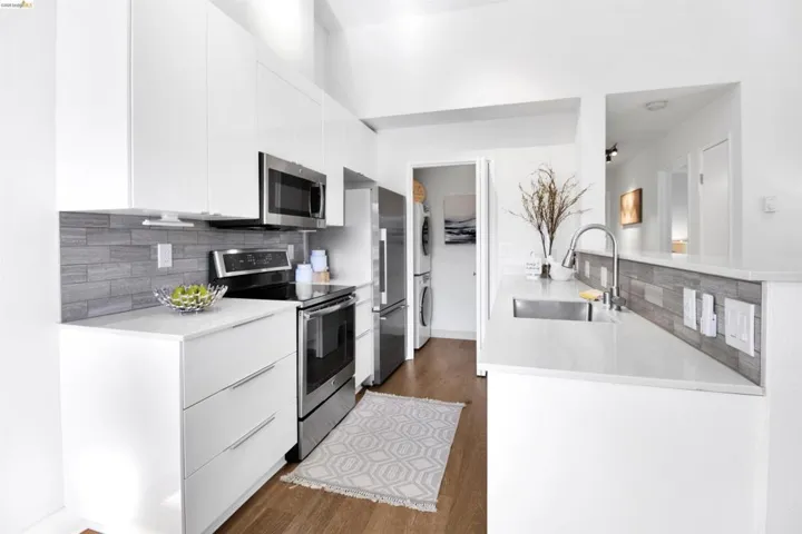 Kitchen with modern cabinets, stainless steel appliances, light stone countertops, and white cabinetry