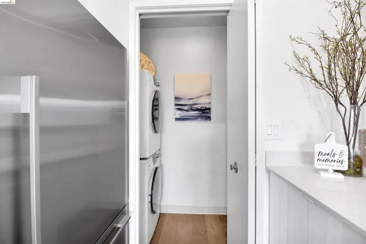 Laundry room featuring wood finished floors and stacked washer and clothes dryer