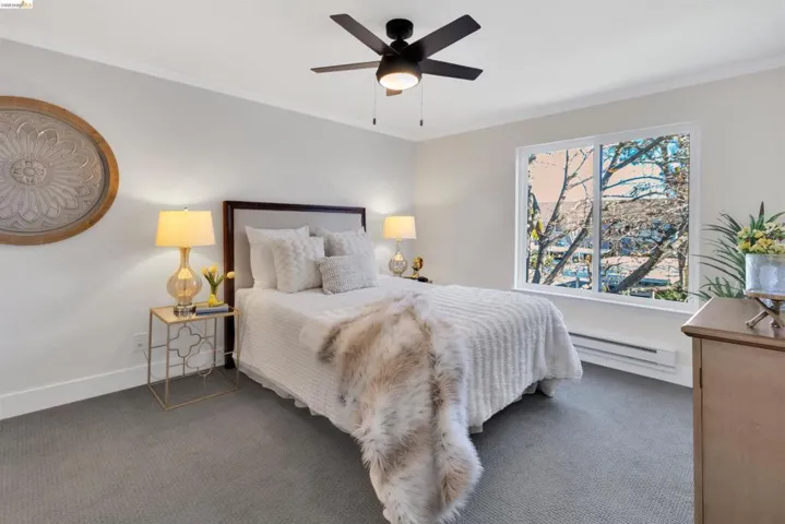 Carpeted bedroom featuring crown molding, a baseboard radiator, and a ceiling fan