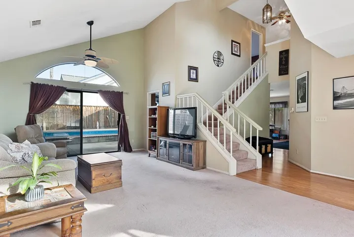 Carpeted living room featuring a ceiling fan, lofted ceiling, and crown molding