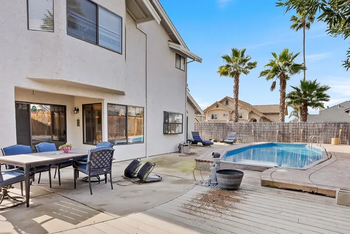 View of swimming pool with outdoor dining space, a fenced backyard, a deck, and patio surround