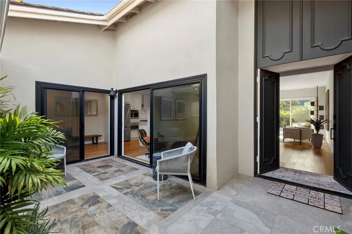 Welcoming covered entry courtyard with modern finishes and lush greenery creating a private approach to the home.