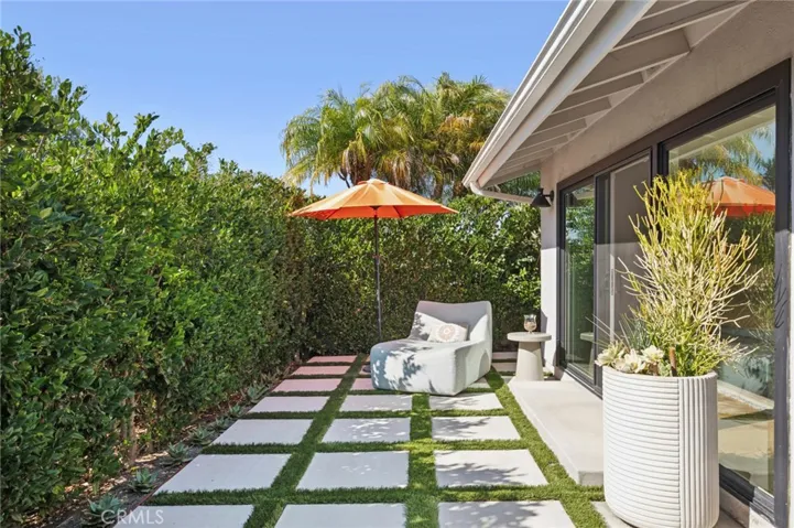 Charming outdoor lounge space with modern paver design and lush privacy hedges, creating a peaceful setting to relax or enjoy morning coffee.
