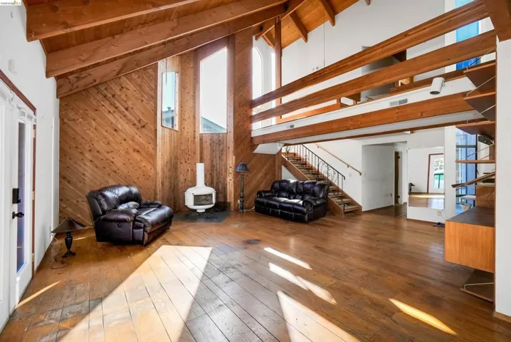 Living area with wood-type flooring, wooden walls, and a high wood beamed ceiling