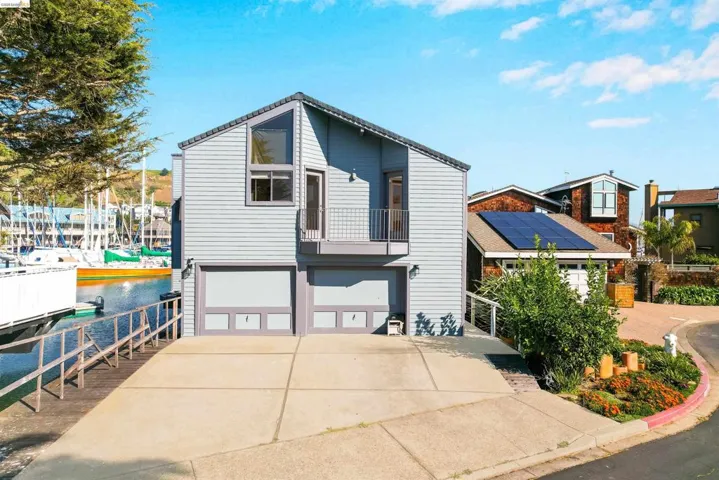 View of front of property featuring a balcony, a garage, driveway, and a water view