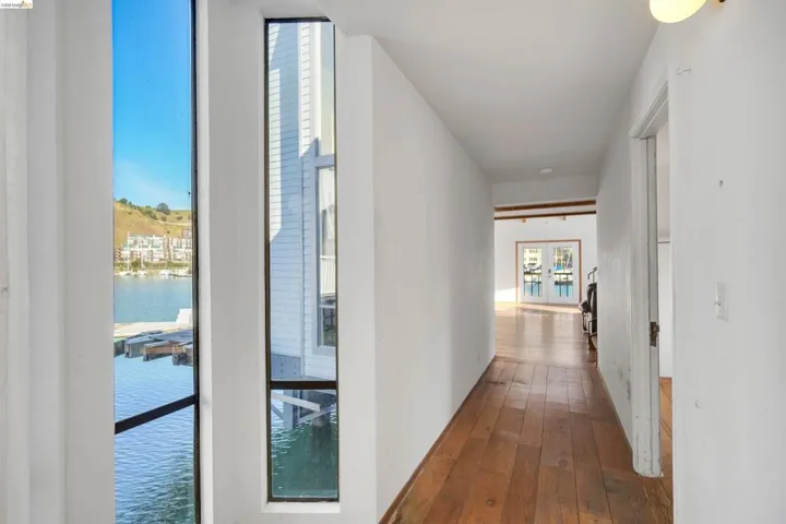 Corridor featuring a water view, dark wood-style floors, floor to ceiling windows, and french doors
