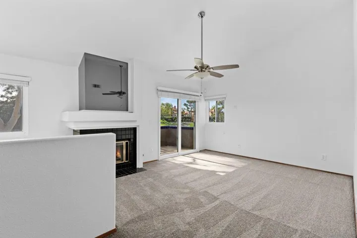 Another view of the primary bedroom with fireplace and balcony overlooking golf course.