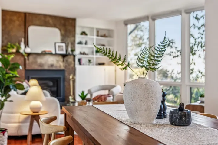 Living area with built in shelves, a glass covered fireplace, and wood finished floors