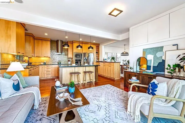 Kitchen featuring a breakfast bar, hanging light fixtures, an island with sink, stainless steel appliances, and tasteful backsplash