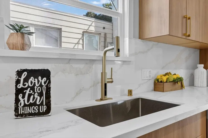 Kitchen view of light stone counters, modern cabinets, and tasteful backsplash