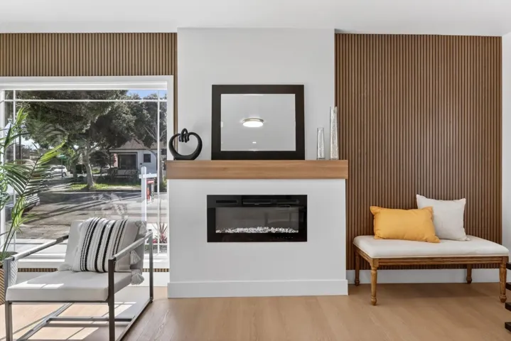 Sitting room featuring a glass covered fireplace, wood finished floors, and wood walls