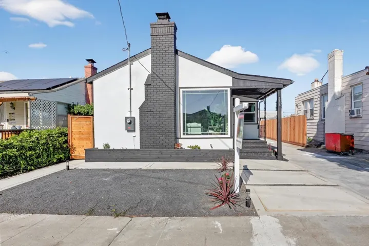 View of front of home featuring stucco siding, a chimney, and brick siding