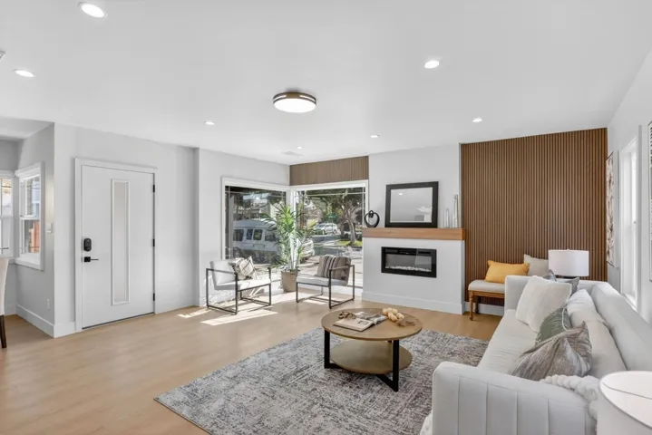 Living room with light wood-style flooring, a glass covered fireplace, and recessed lighting