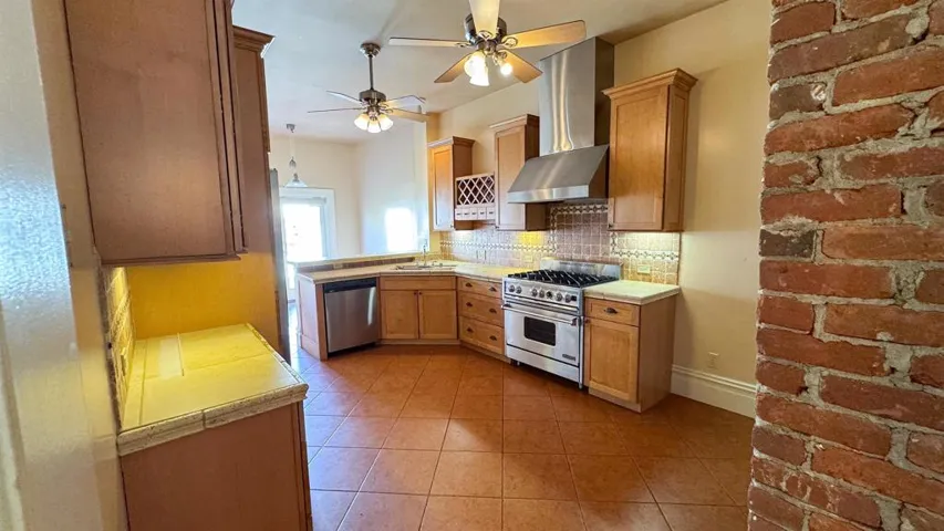 Kitchen with tasteful backsplash, stainless steel appliances, tile counters, a ceiling fan, and light tile patterned floors