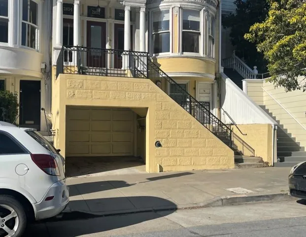 View of building exterior featuring stairs, a garage, and driveway