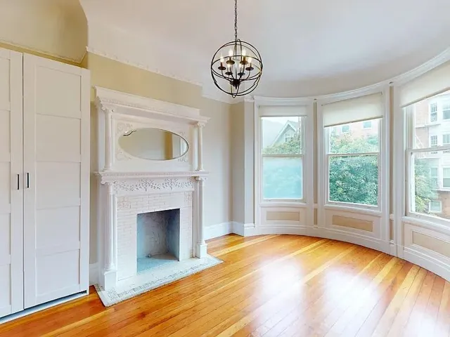 Unfurnished living room with a chandelier, light wood-type flooring, ornamental molding, and a fireplace