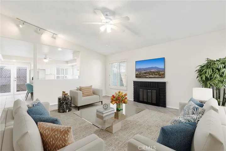 Living room with gas fireplace, vaulted ceiling, and open to kitchen (virtual staging)