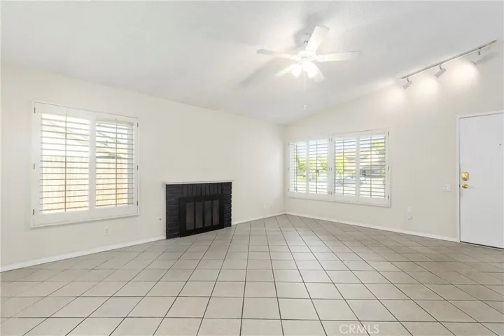 Living room with gas fireplace, vaulted ceiling, and open to kitchen