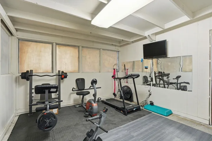 Exercise room with beam ceiling and wood walls