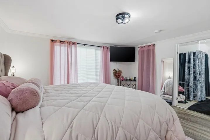 Bedroom with wood finished floors and ornamental molding
