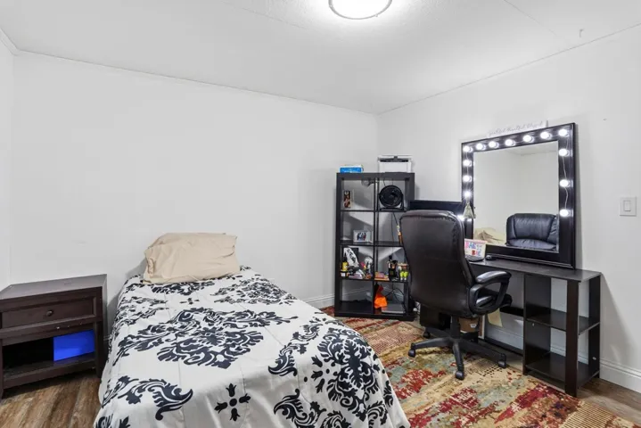 Bedroom with dark wood-style flooring and an office area