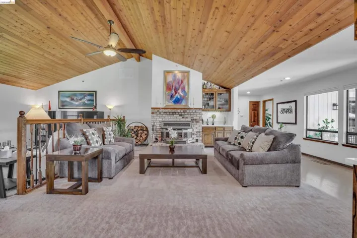 Living area featuring light colored carpet, a high wood beamed ceiling, a fireplace, recessed lighting, and a ceiling fan
