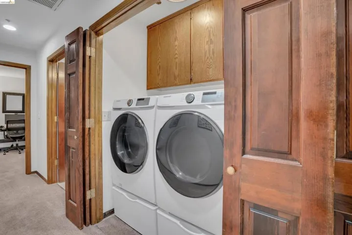 Laundry room featuring cabinet space, light colored carpet, independent washer and dryer, and recessed lighting