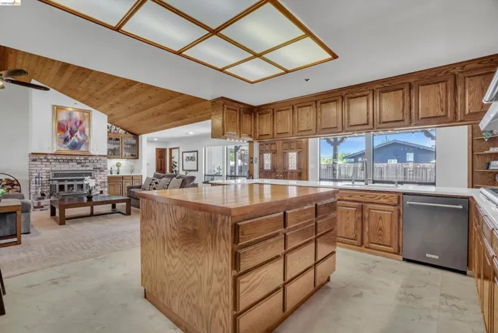 Kitchen featuring a kitchen island, open floor plan, plenty of natural light, stainless steel dishwasher, and a vaulted wooden ceiling