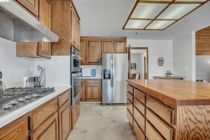 Kitchen with stainless steel appliances, wood finish cabinets, butcher block countertops, and a center island