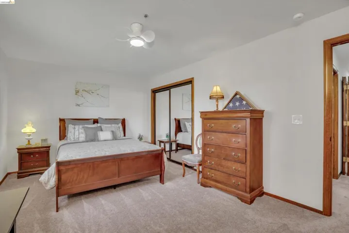 Bedroom with light carpet, a closet, and a ceiling fan