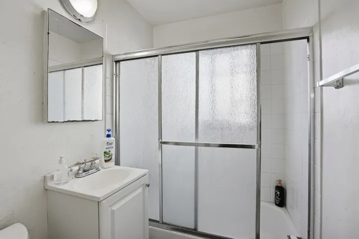 Bathroom featuring shower / bath combination with glass door and vanity