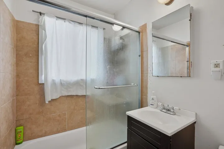 Bathroom featuring vanity and combined bath / shower with glass door