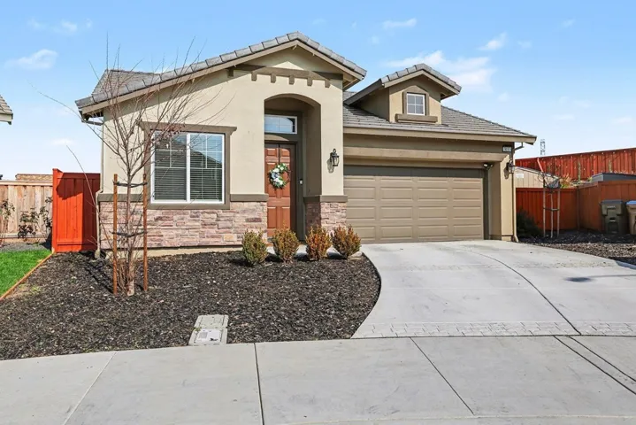 View of front of home with concrete driveway, stucco siding, stone siding, and an attached garage