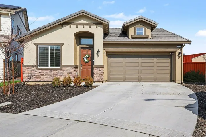 View of front of house with stucco siding, driveway, a garage, and stone siding