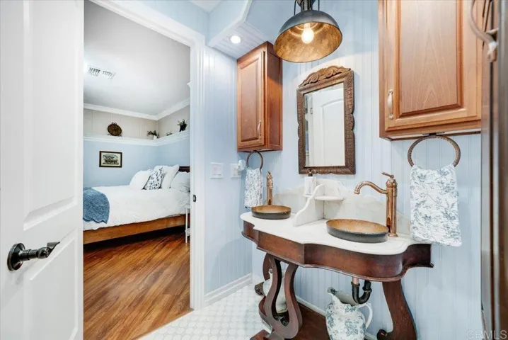 Bathroom with pedestal sink, framed mirror, and charming design details.