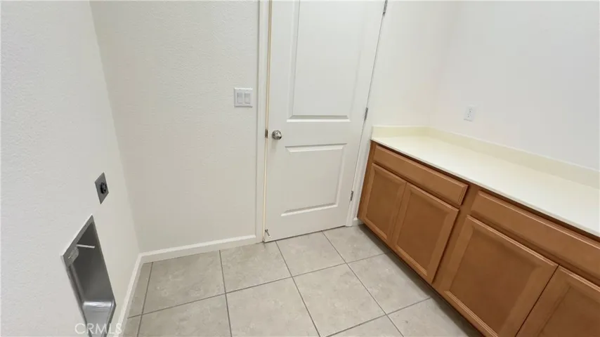 Convenient indoor laundry room with built-in cabinetry and plenty of storage space