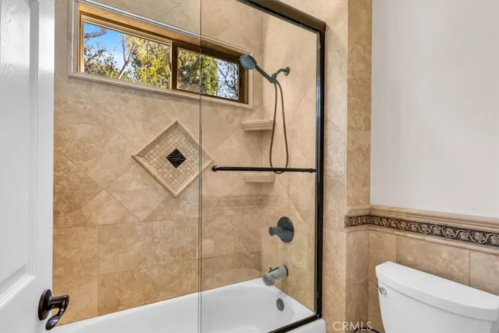 Jack-n-Jill bath includes glass enclosed shower/tub combo