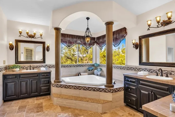 Soaking tub is ideally placed in the corner between dual vanities and windows overlooking backyard